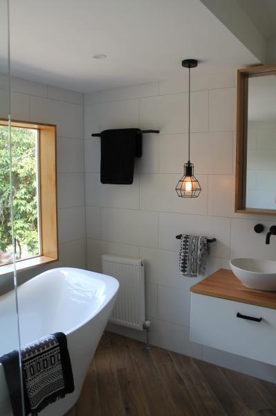 Modern bathroom with freestanding bath, timber vanity and pendant light by a window