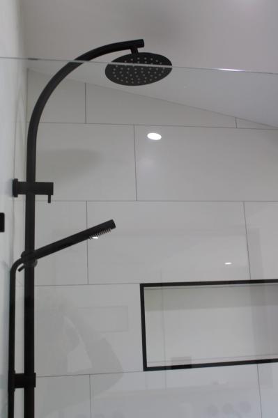 Matte black shower set with rainfall head against white tiled bathroom wall