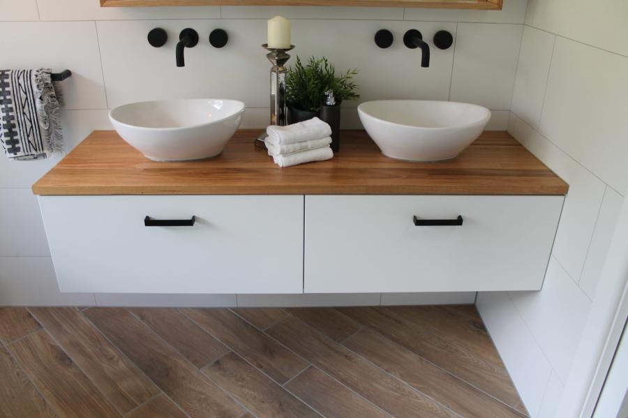 Double basin bathroom vanity with timber benchtop and wall-mounted black tapware