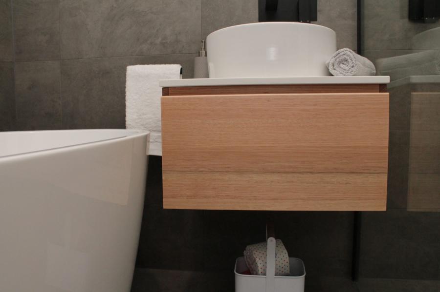 Modern bathroom vanity with vessel basin beside bathtub in a tiled bathroom