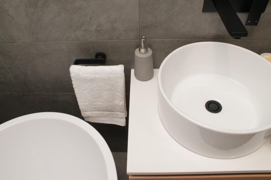 Modern bathroom vanity with white vessel basin, black tapware and grey tiled wall