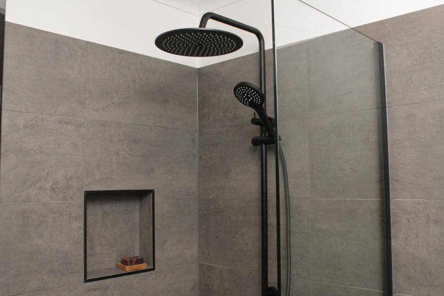 Modern walk-in shower with charcoal tiles, black tapware and recessed wall niche