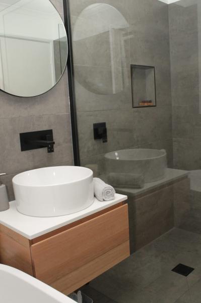 Modern grey bathroom with wall-hung timber vanity, vessel basin and glass shower over bath
