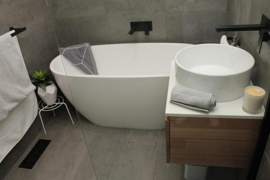 Modern grey bathroom with freestanding bath, round basin vanity and black tapware
