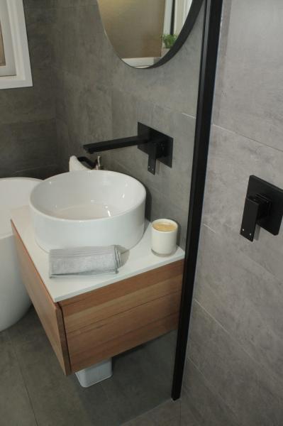 Modern bathroom vanity with basin, round mirror and matte black shower fixtures