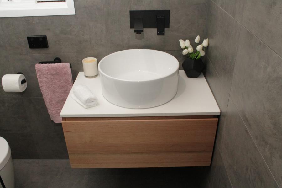 Floating timber vanity with round basin in a modern grey tiled bathroom