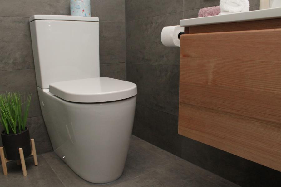 Modern wall-hung timber vanity beside a white toilet in a grey tiled bathroom