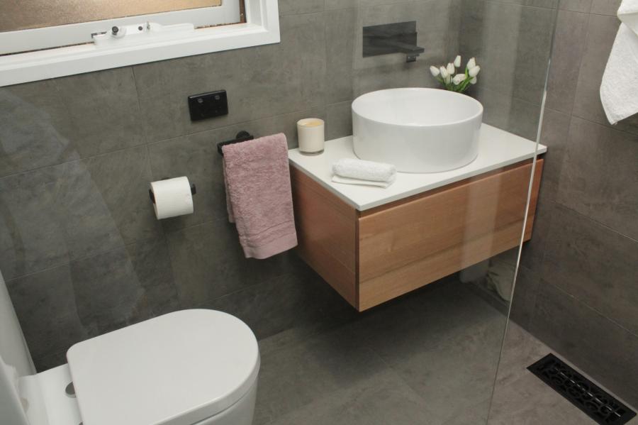Modern grey tiled bathroom with wall-hung vanity, round basin and walk-in shower