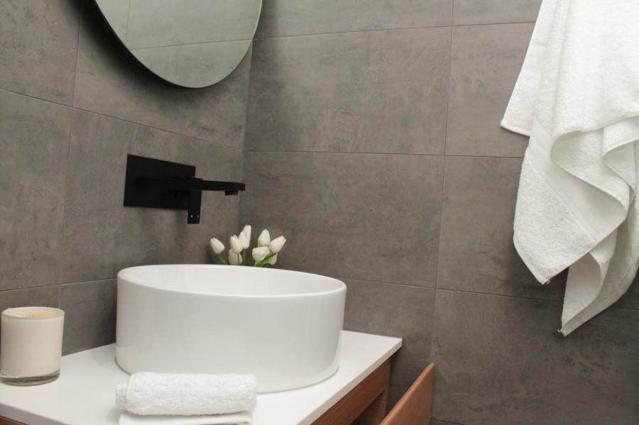 Modern bathroom vanity with round basin, grey wall tiles and black wall-mounted tapware