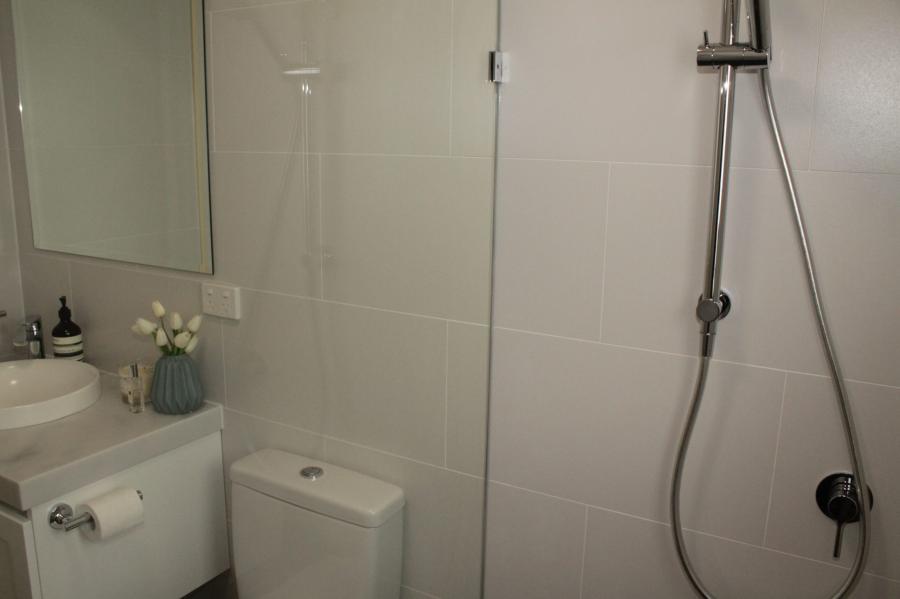 Compact white bathroom with glass shower, toilet and basin vanity