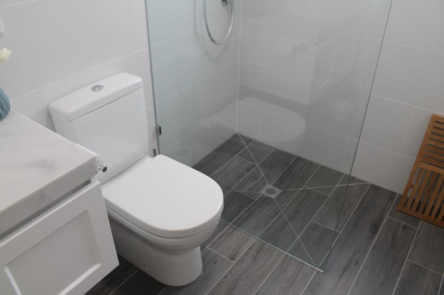Modern bathroom with walk-in shower, wall-mounted vanity and grey floor tiles
