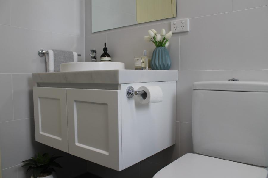 Modern white floating vanity beside toilet in a tiled bathroom