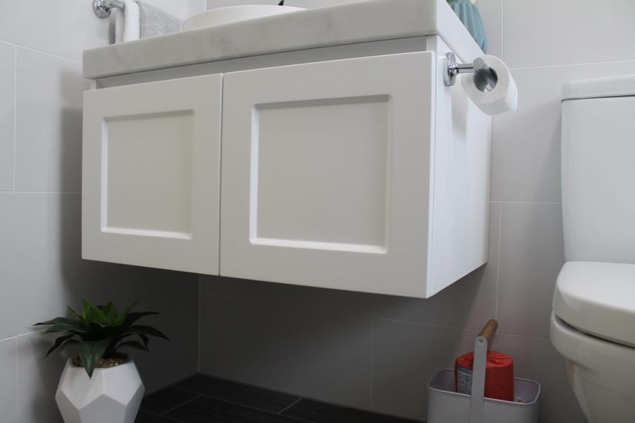 Floating white bathroom vanity beside toilet in a modern compact bathroom
