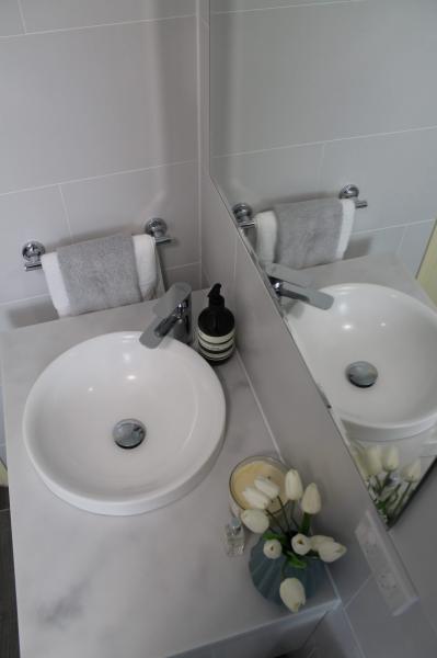 Round white basin vanity with chrome tap beside wall mirror and folded hand towel