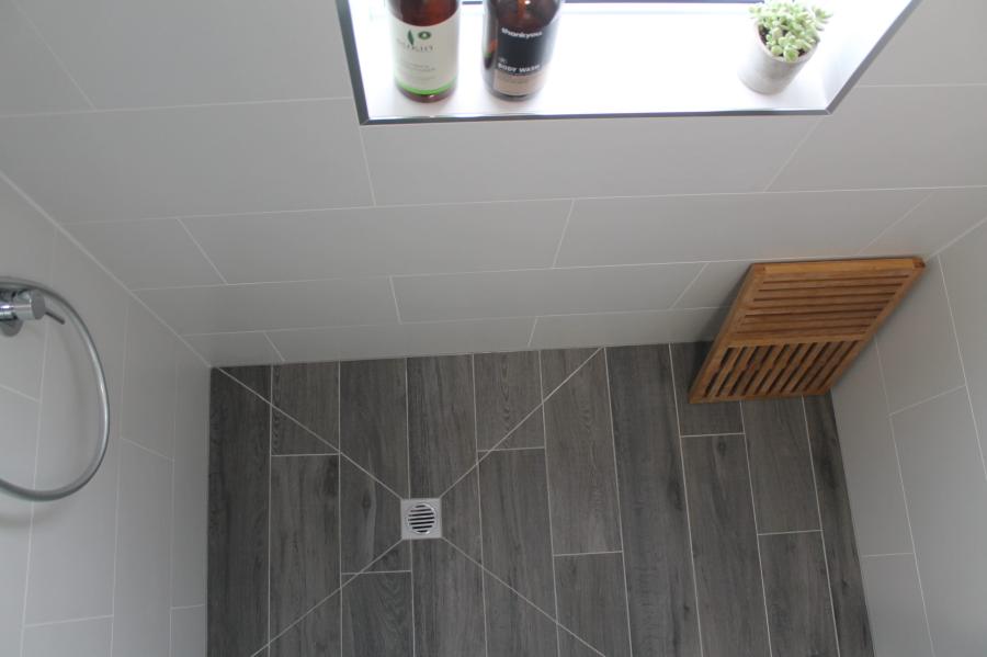 Grey tiled shower floor with wall niche and timber shower seat