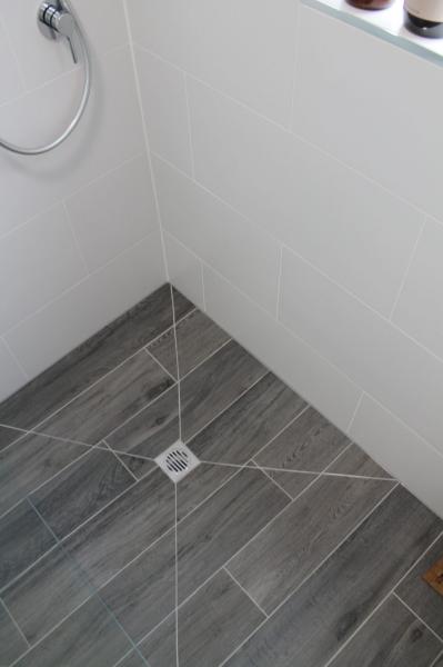 Grey tiled shower floor with central waste and white wall tiles