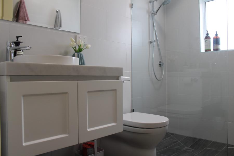 Modern white bathroom with floating vanity, toilet and glass walk-in shower