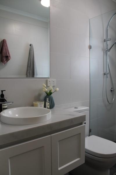 Modern white bathroom with vessel basin, vanity, toilet and glass shower