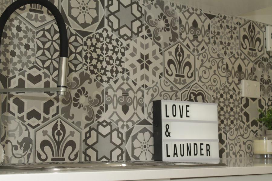 Decorative patterned tile splashback above a laundry sink with a lightbox sign reading Love & Launder