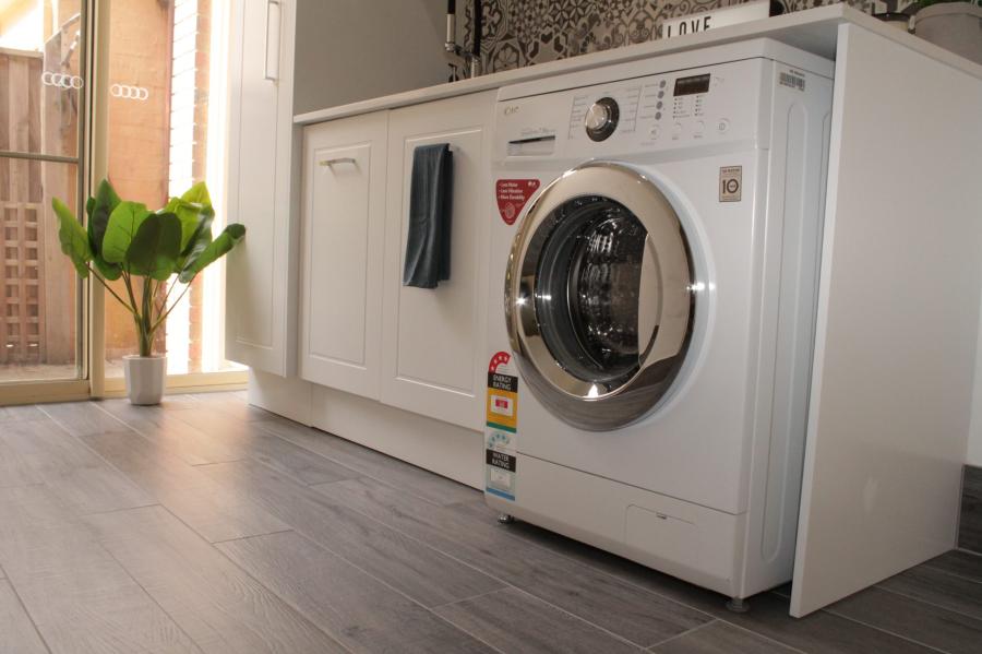 White front-loading washing machine built into custom laundry cabinetry