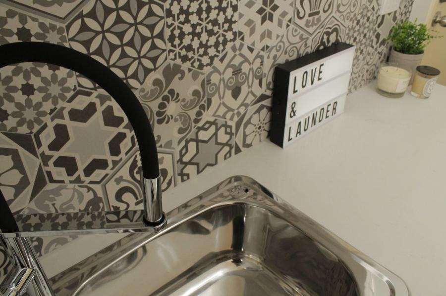 Laundry sink with matte black tap and patterned tiled splashback
