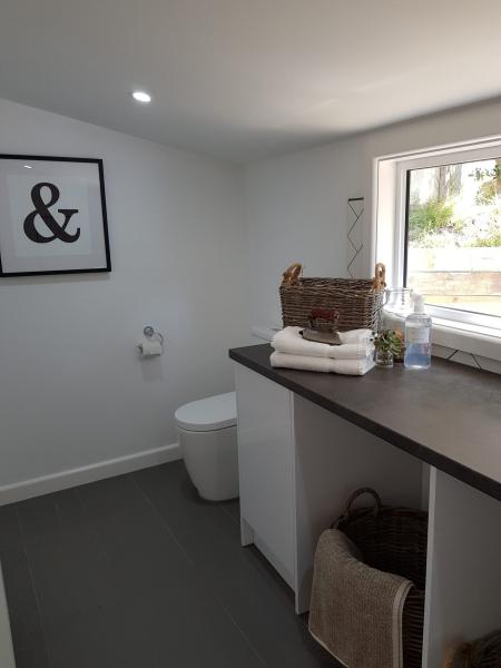 Modern powder room with toilet, vanity shelf, window and folded towels