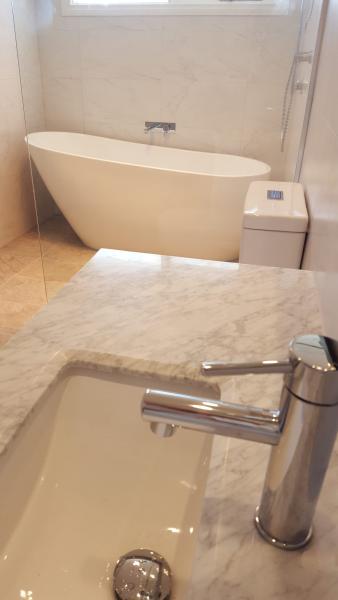 Modern bathroom with stone vanity, chrome tapware, freestanding bath and concealed cistern toilet