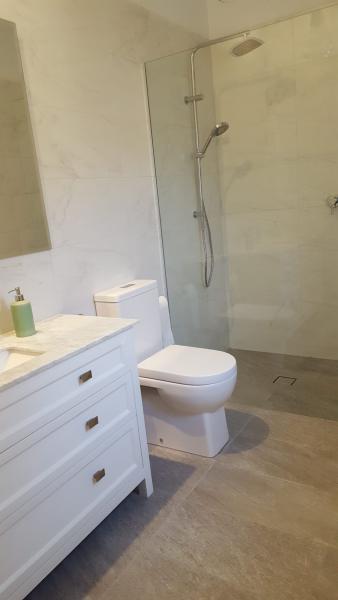 Modern white bathroom with vanity, wall-hung toilet and glass walk-in shower