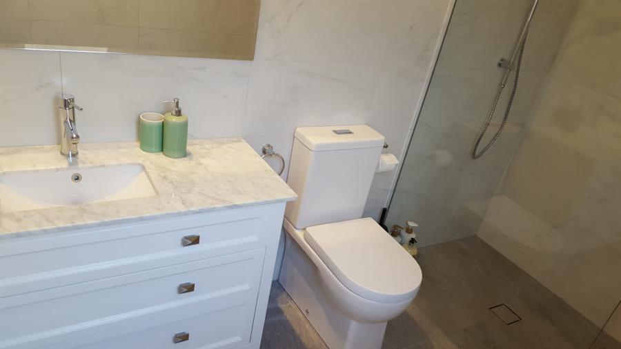 Modern white bathroom vanity, toilet and walk-in shower with frameless glass screen