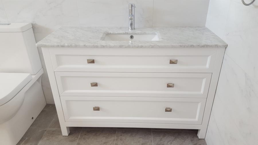 White bathroom vanity with three drawers, stone benchtop and inset basin beside a toilet
