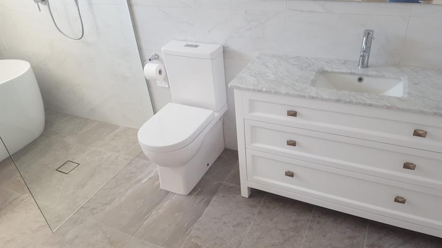 Modern white bathroom vanity and toilet with light grey floor tiles