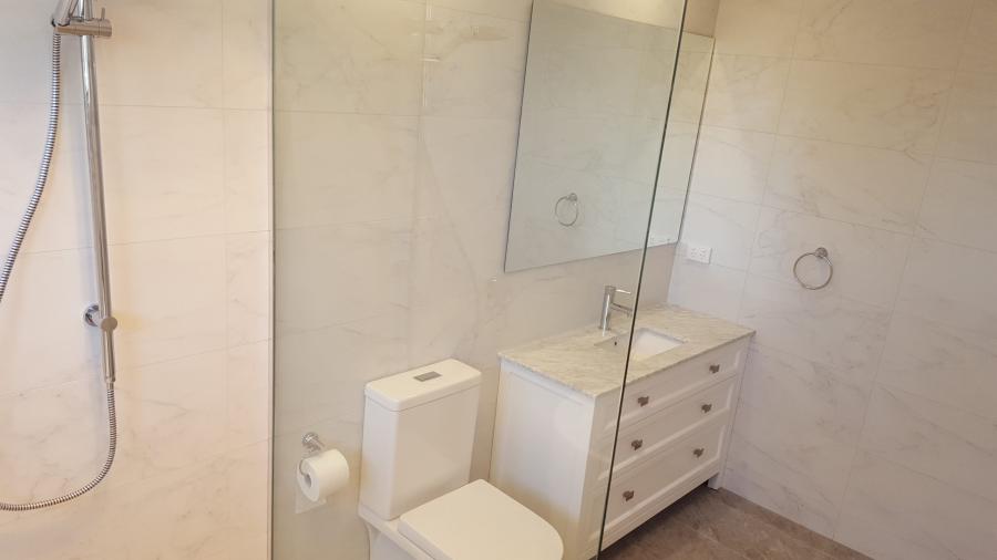 Modern bathroom with wall-hung vanity, toilet, shower and mirrored cabinet