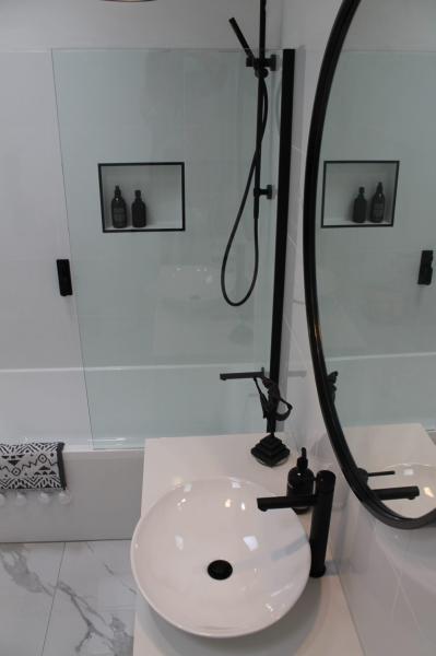 Modern bathroom vanity with round basin, mirror and black shower fittings