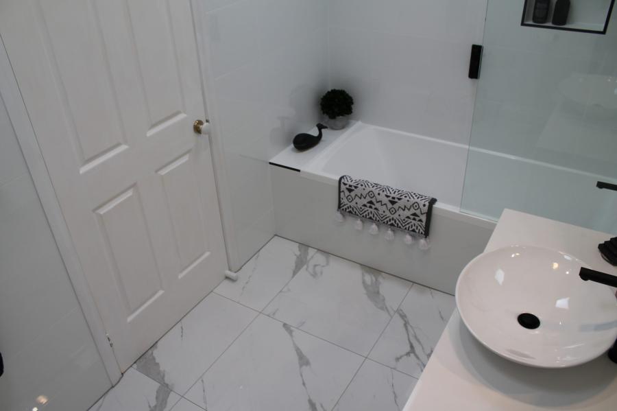 Modern white bathroom with freestanding basin, bath and marble-look floor tiles