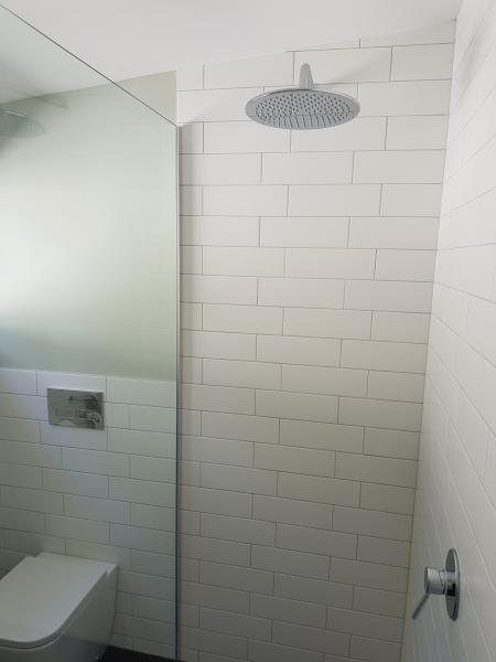 Walk-in shower with white subway tiles, rainfall shower head and glass screen