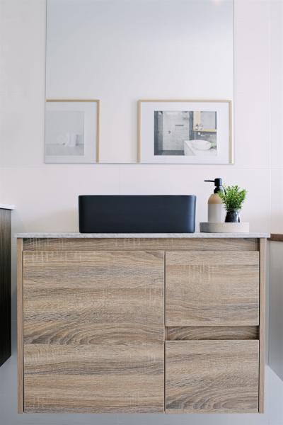 Timber bathroom vanity with black basin, white walls and small framed artwork