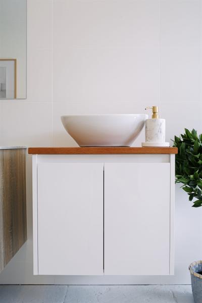 White wall-hung vanity with vessel basin and brushed brass tapware in a modern bathroom