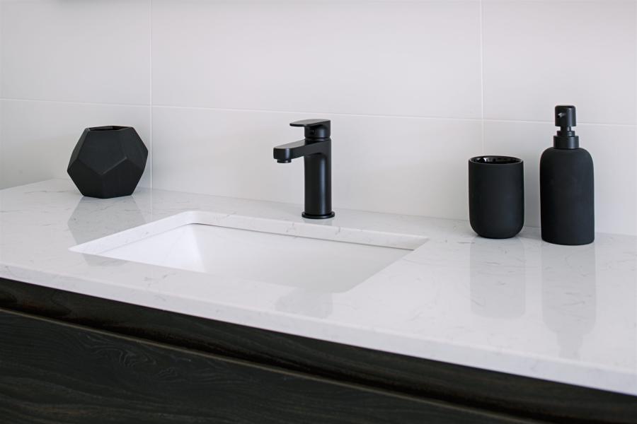 White vanity benchtop with inset basin, matte black tapware and matching bathroom accessories