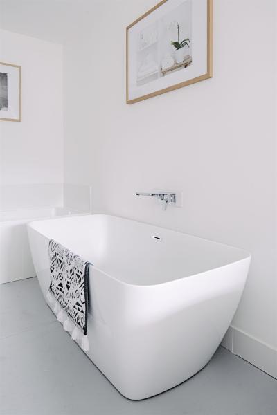 Freestanding white bathtub in a minimalist modern bathroom with framed wall art