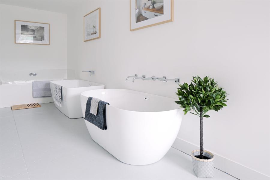 Bright white bathroom with freestanding bath, bidet, toilet and potted plant