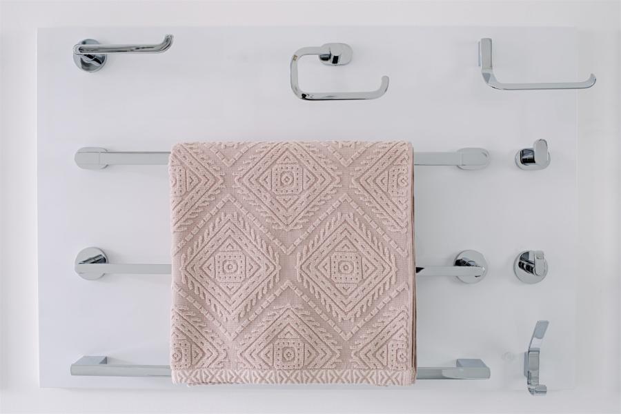 Wall display of chrome bathroom accessories with a blush pink patterned towel