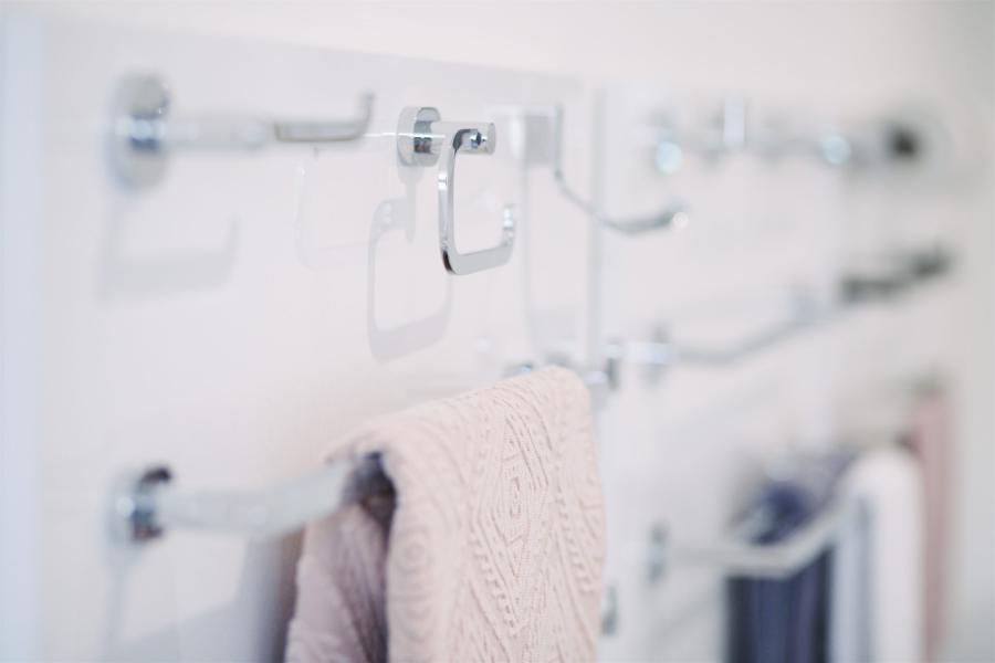 Chrome bathroom accessories display with towel rail and hooks on a white wall