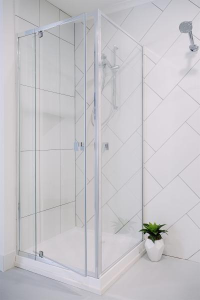 Frameless glass corner shower with white tiled walls and chrome shower fixtures