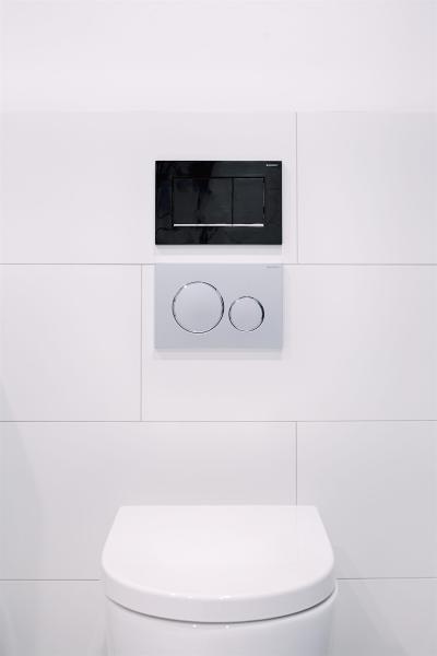 Wall-hung toilet with concealed cistern and dual flush plate on white tiled bathroom wall