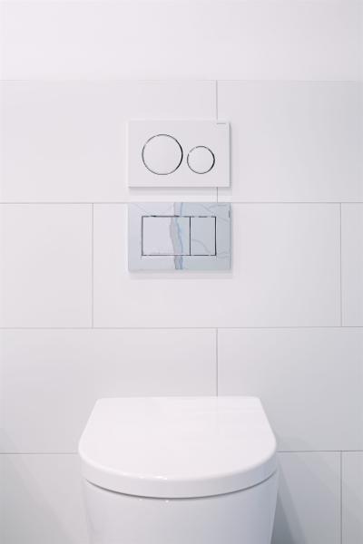 Wall-hung toilet with dual flush plates on white tiled bathroom wall