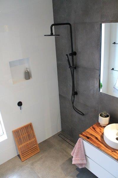Modern walk-in shower with black tapware, timber vanity and concrete-look tiles