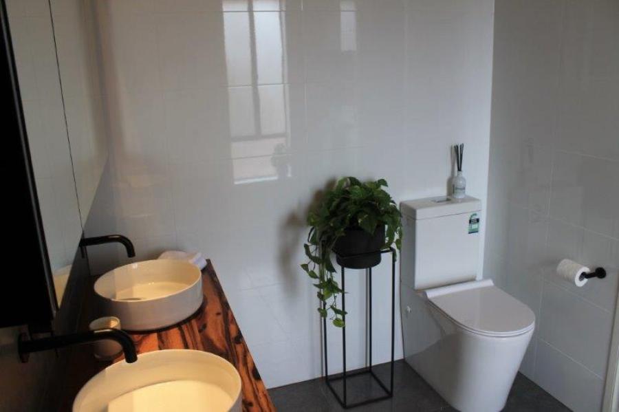 Modern bathroom with double vessel basins, timber vanity and wall-hung toilet
