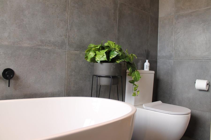 Modern bathroom with freestanding bath, wall-hung toilet and grey tiled walls