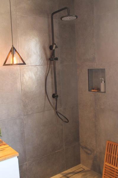 Walk-in shower with matte black fixtures, recessed niche and large grey wall tiles