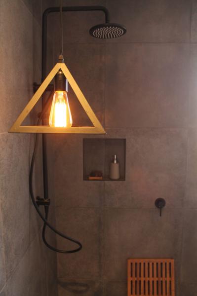 Modern walk-in shower with pendant light, niche shelf and timber stool